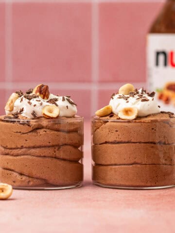 Nutella mousse piped into fancy serving cups, garnished with whipped cream and chocolate curls for a luxurious look.