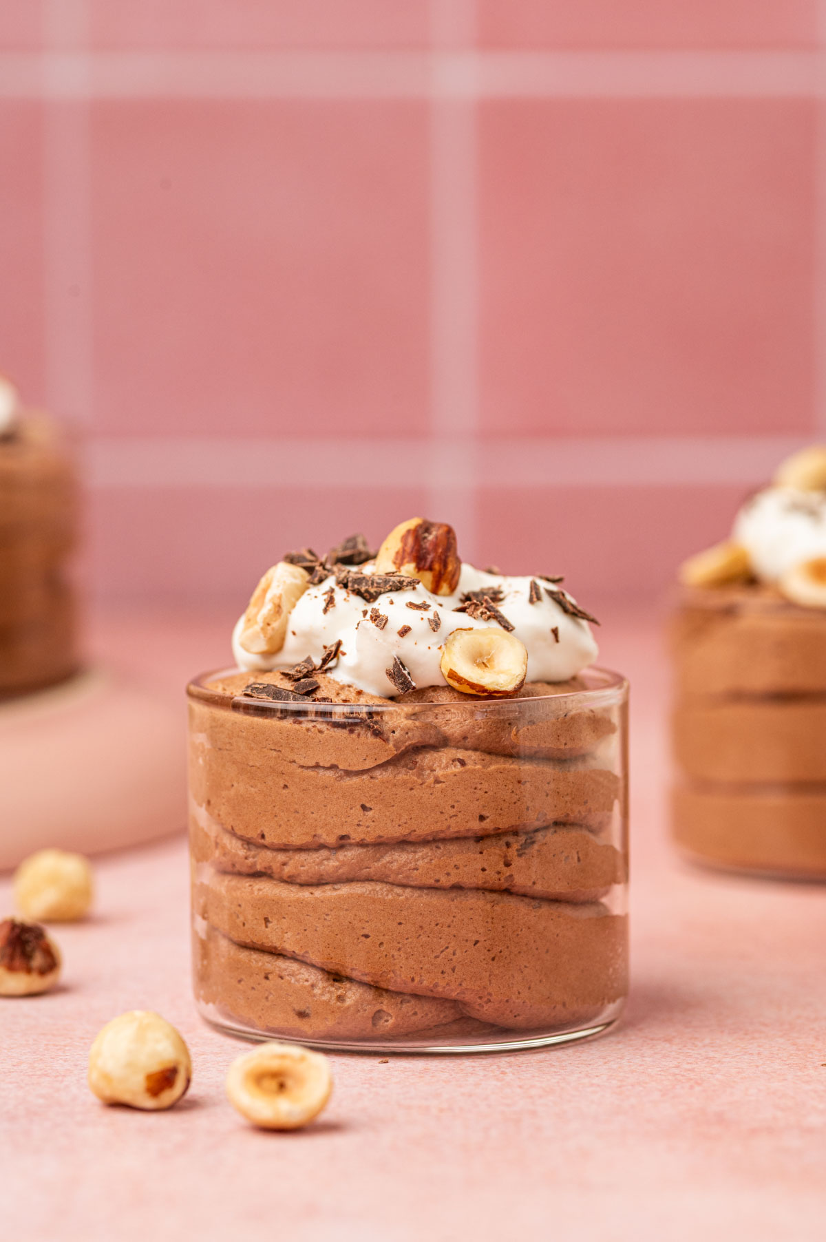 A beautifully styled Nutella mousse dessert  topped with whipped cream, chocolate shavings, and chopped hazelnuts.