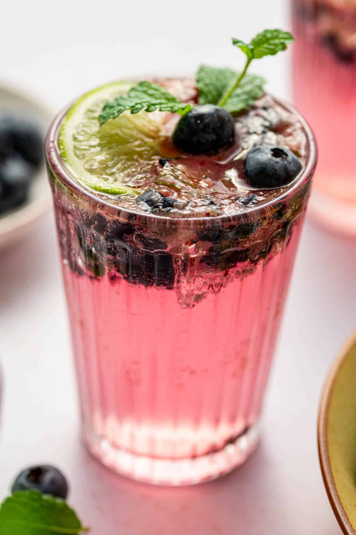 Colorful summer mocktail with blueberries, mint, and fizzy seltzer water.