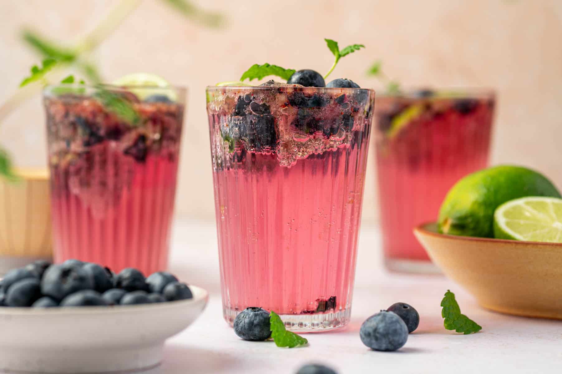 Summer drink idea: blueberry mojito mocktail in a clear glass with blueberries and mint.
