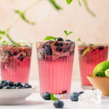 Easy homemade blueberry mojito mocktail served with ice and seltzer water in three. glasses.