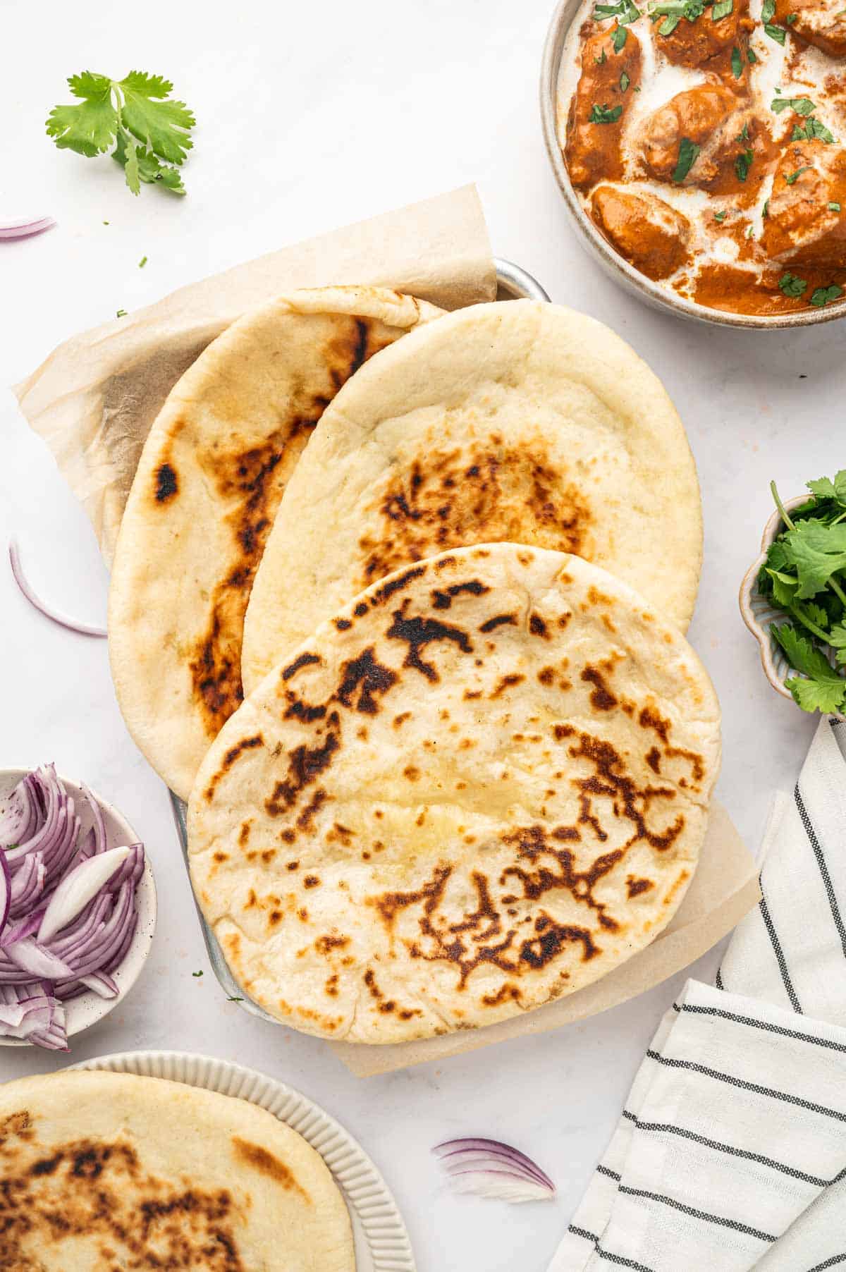 Overhead view of garlic butter cheese naan with chopped herbs on top.