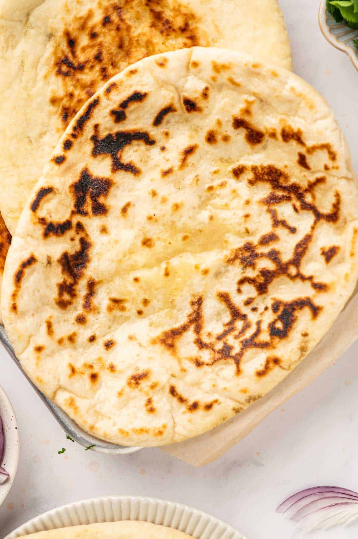 Close-up of freshly cooked naan with melted cheese inside and brushed butter on top.