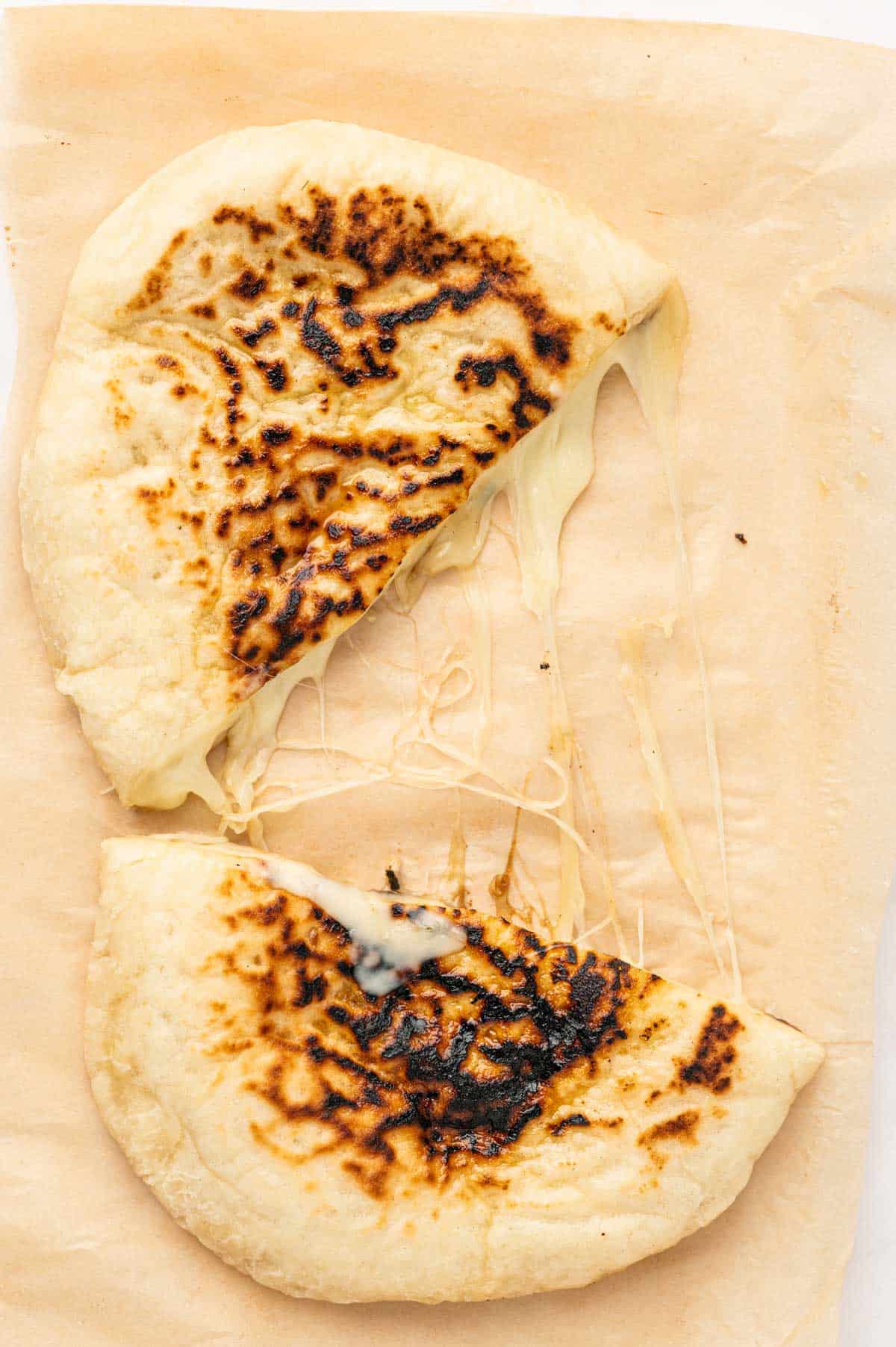 Cheese is melting and oozing from the cheese naan when cutting into halves.