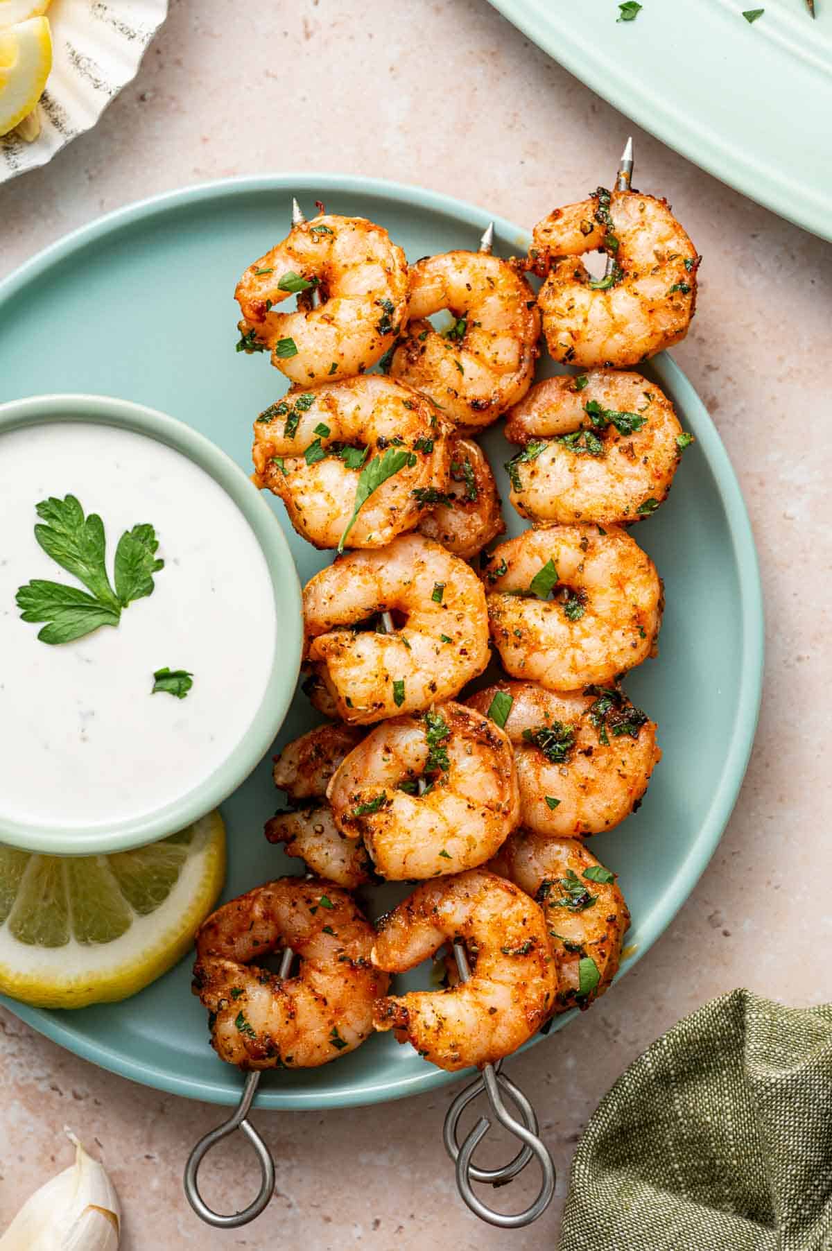 Skewered shrimp seasoned with herbs and spices, baked to perfection and served on a platter with dipping sauce.
