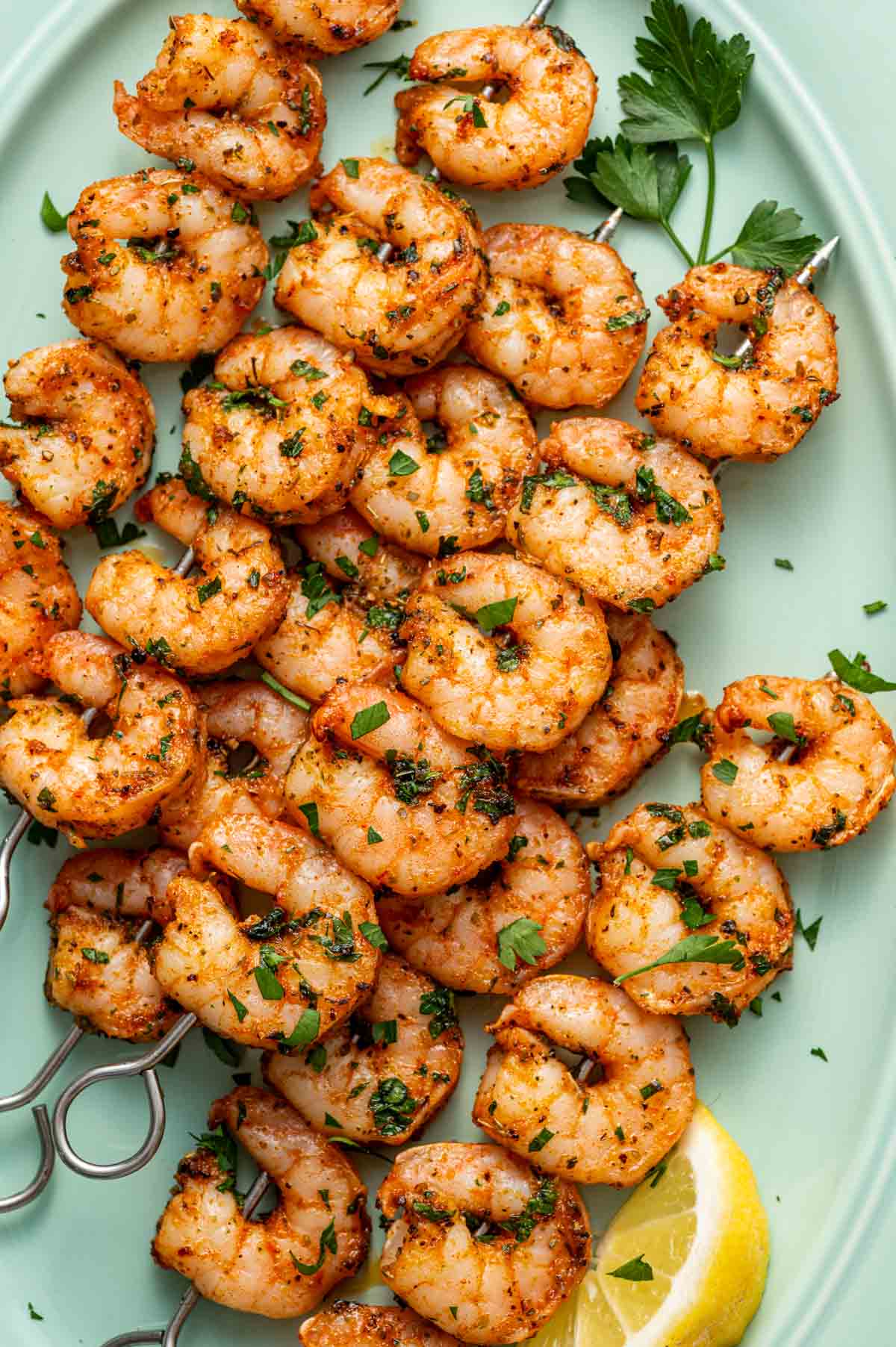 Overhead shot of baked shrimp skewers baked to perfection and served on a gren platter.