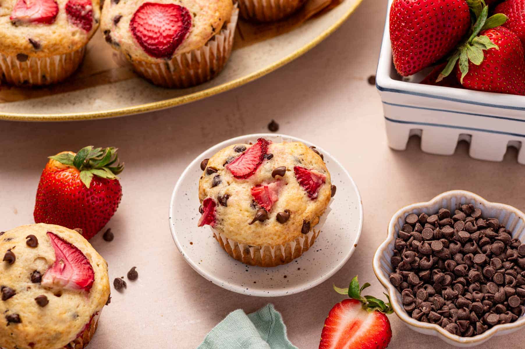 Bakery-style strawberry chocolate chip muffins topped with extra mini chocolate chips.
