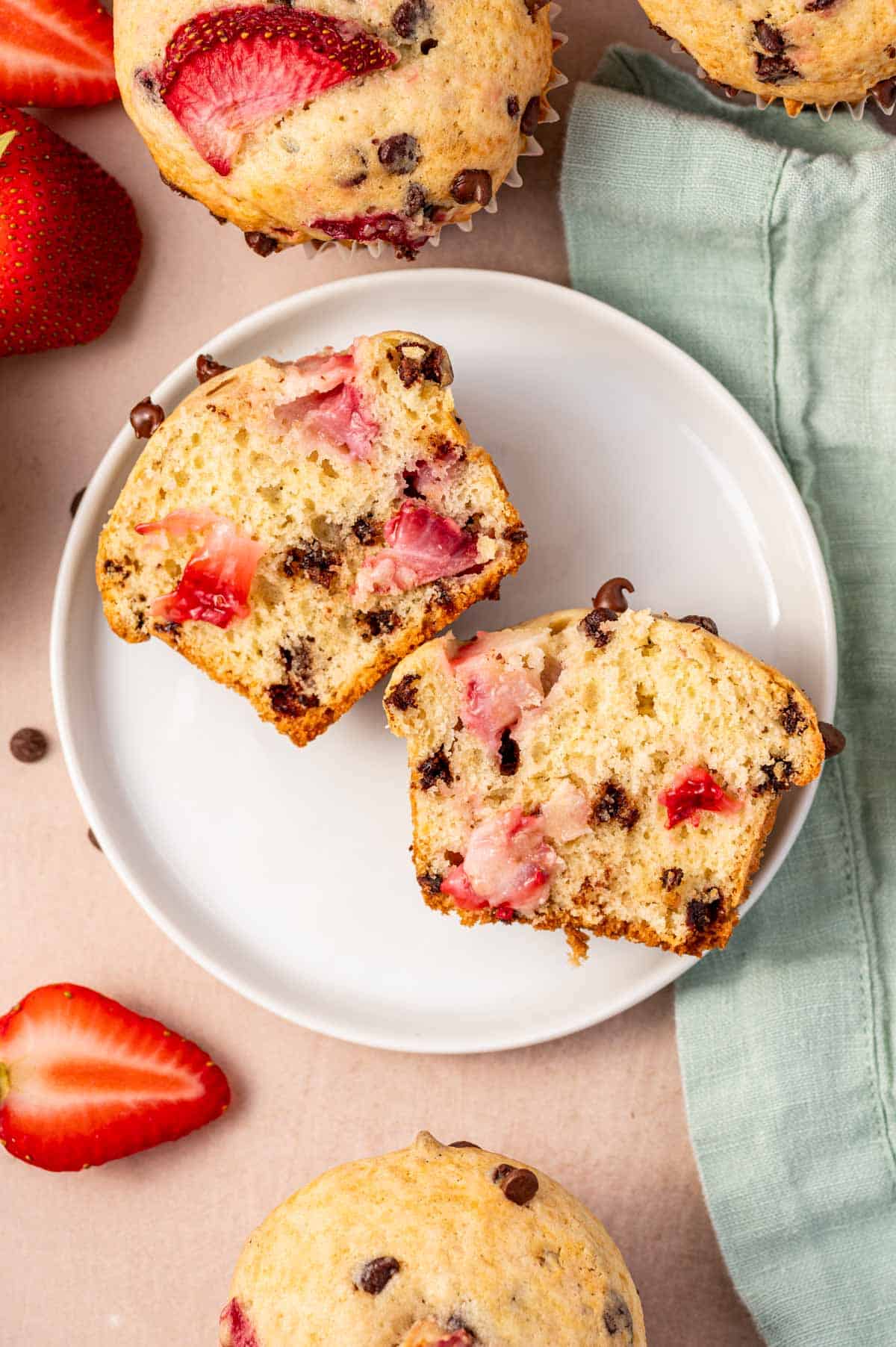 Strawberry chocolate chip muffin broken in half showing juicy strawberries inside.