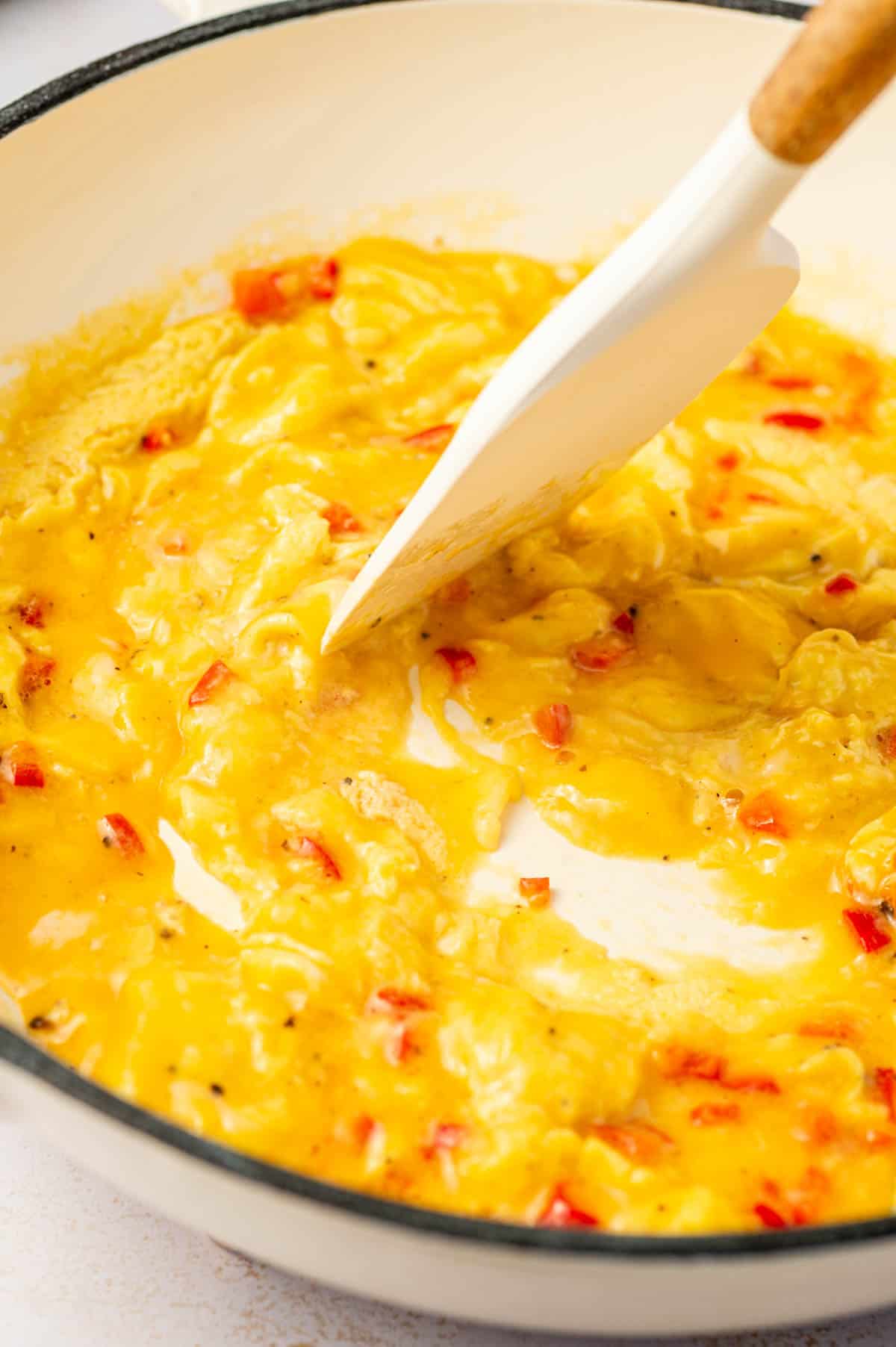 Easy chili scrambled eggs in a nonstick pan with a rubber spatula folding the eggs.