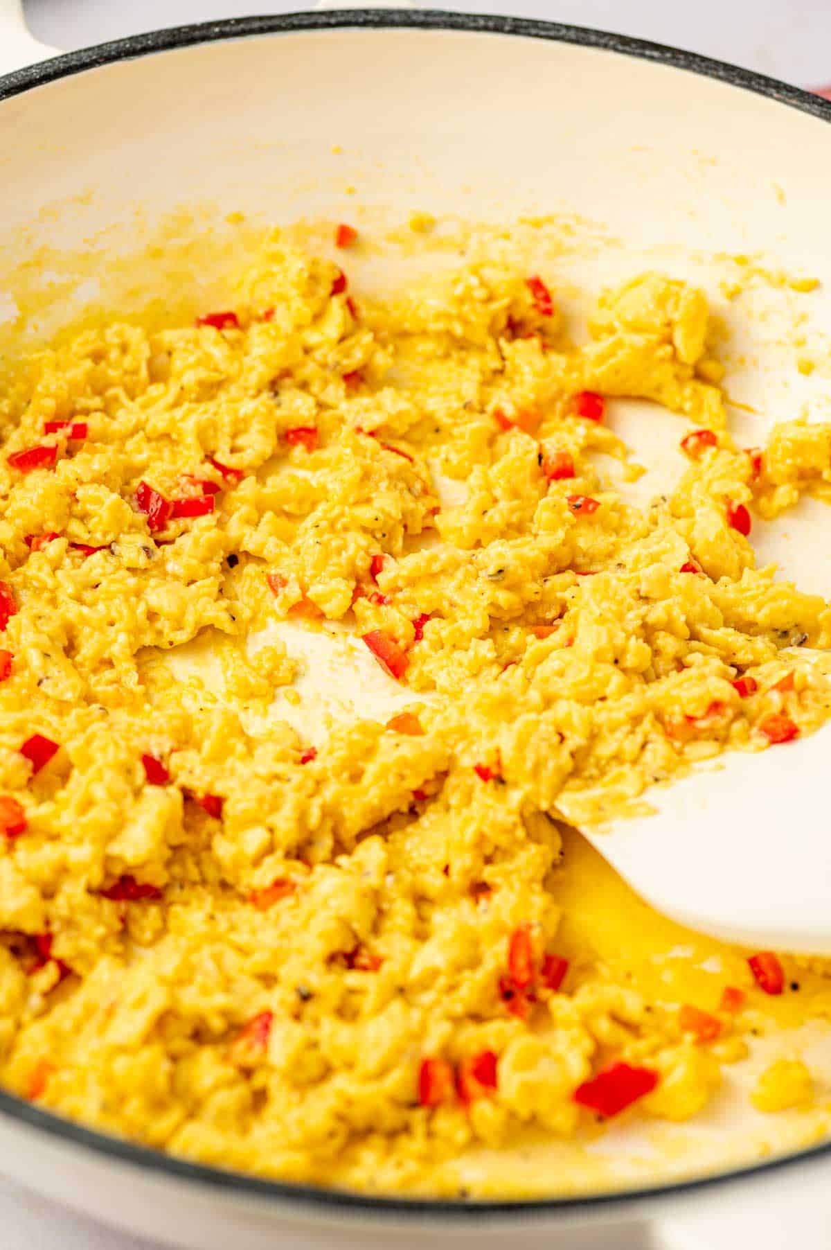Easy chili scrambled eggs in a nonstick cast iron pan with a rubber spatula folding the eggs.