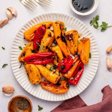 Easy roasted sweet peppers on a platter garnished with parsley in a white plate.