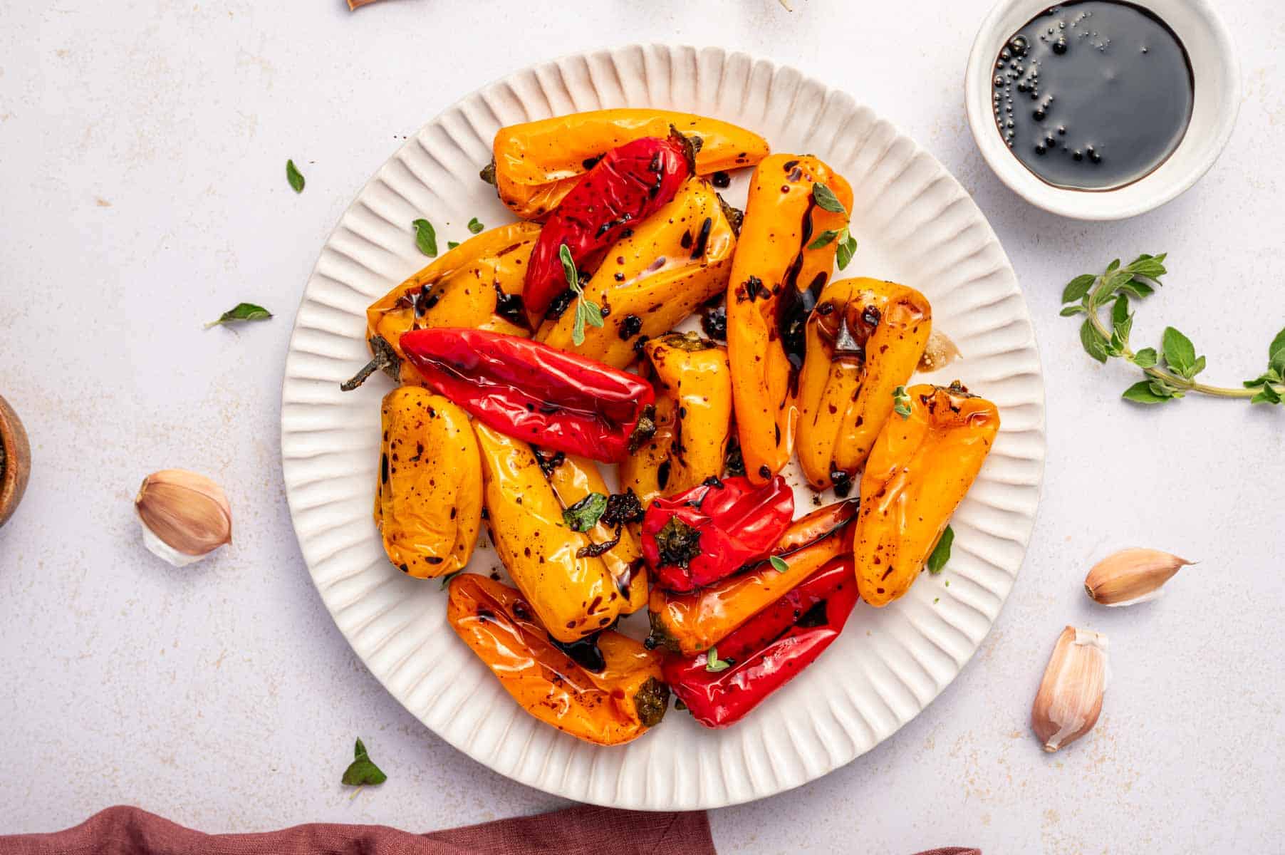 Baked mini peppers with olive oil and garlic on a white plate.