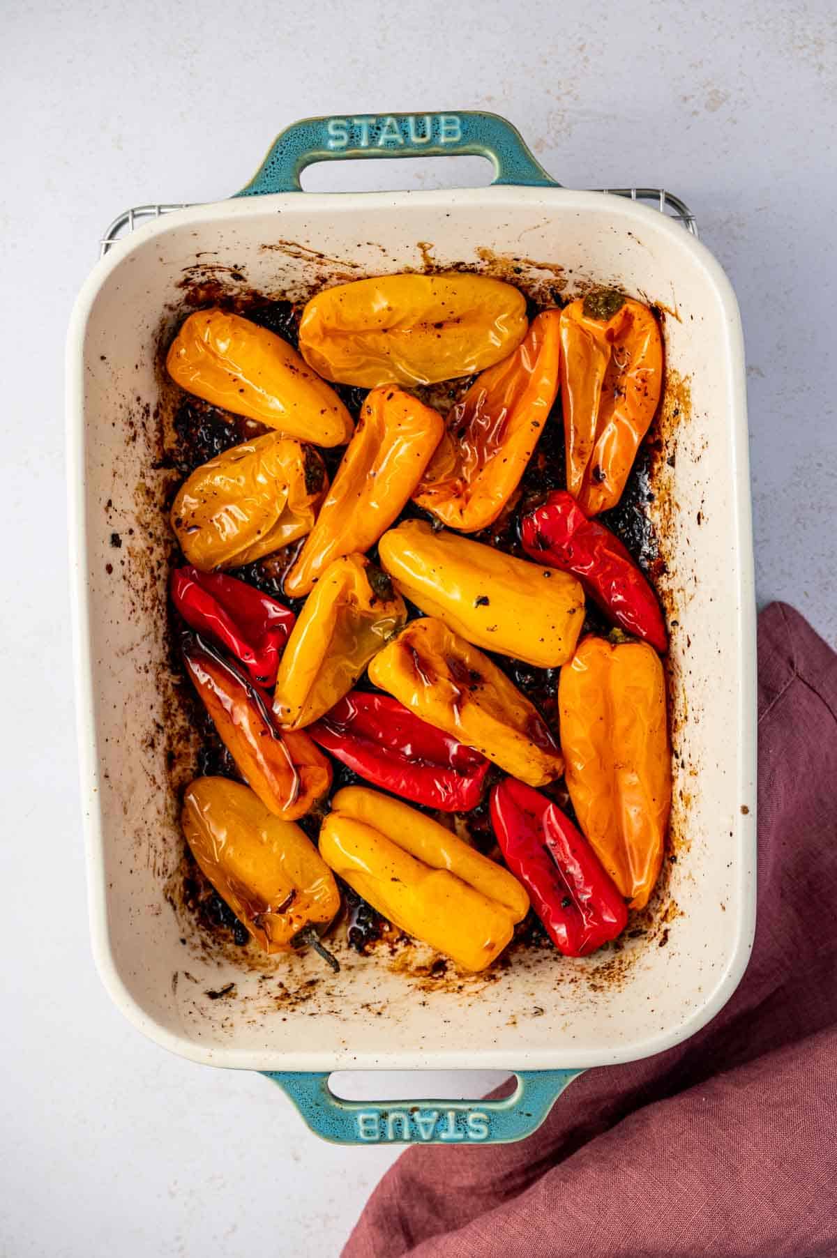 Baked mini peppers with olive oil and garlic on a baking dish.