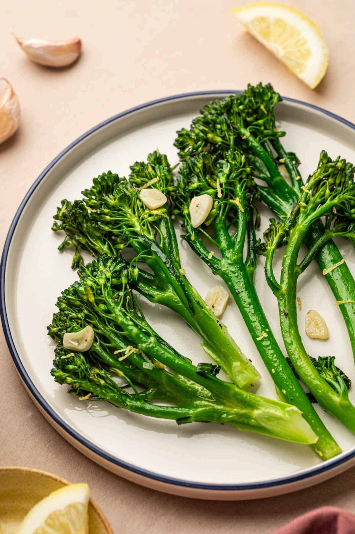 Italian-style broccoletti served on a white plate with lemon wedges