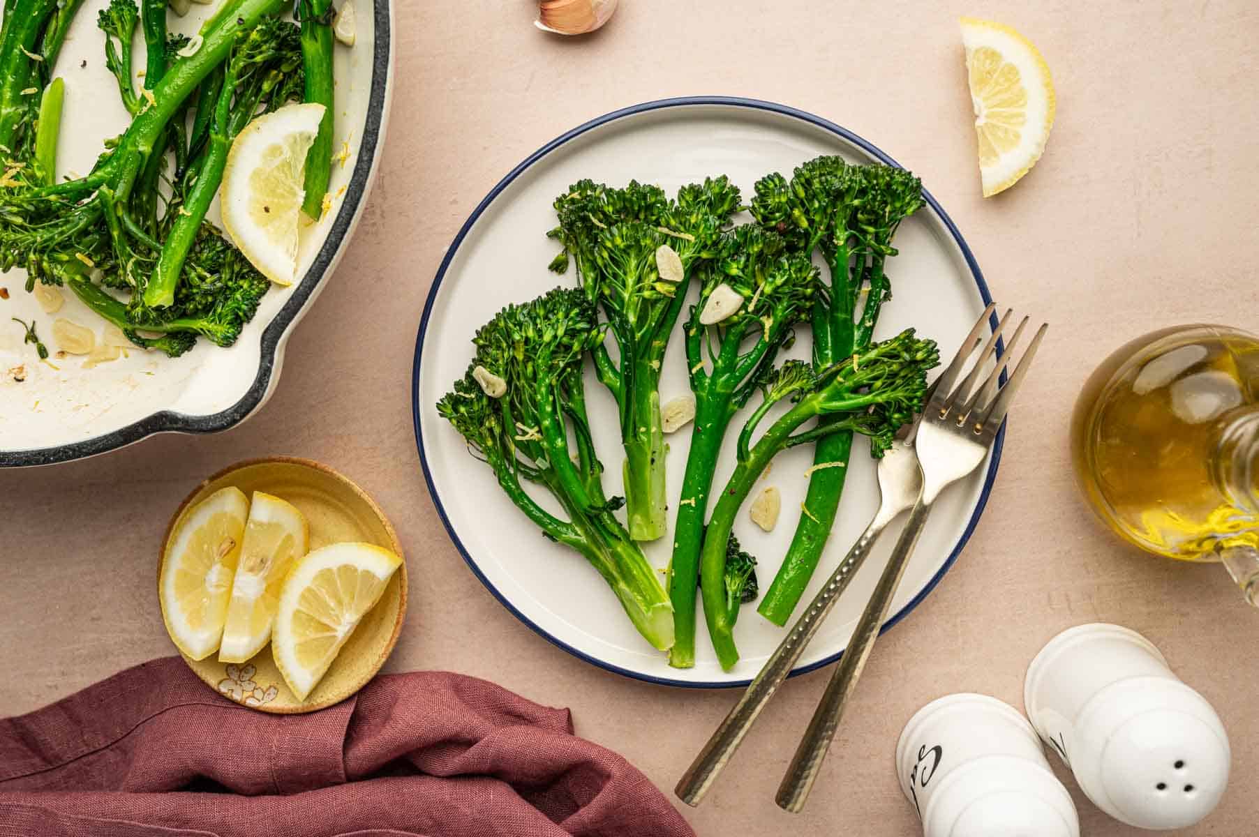 Overhead shot of cooked broccoletti with golden garlic slices in a white plate.