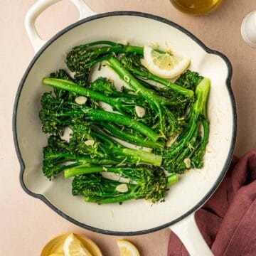 Sautéed broccoletti with garlic in a white cast iron skillet