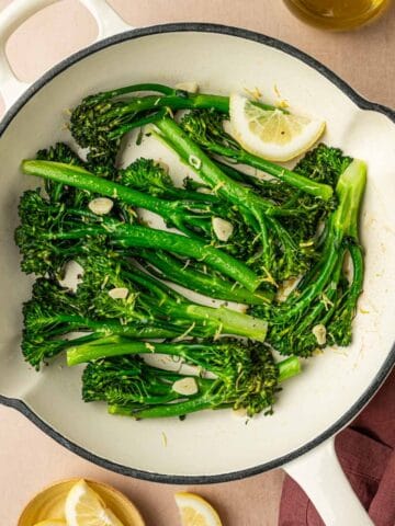 Sautéed broccoletti with garlic in a white cast iron skillet