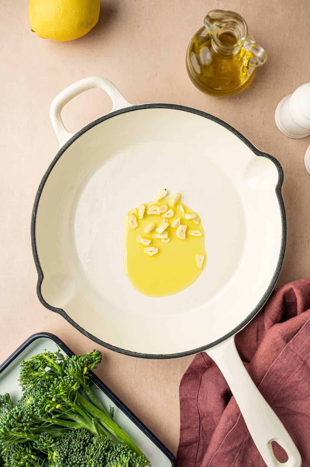 In a white enamel coated skilled olive oil is added along with garlic slices.