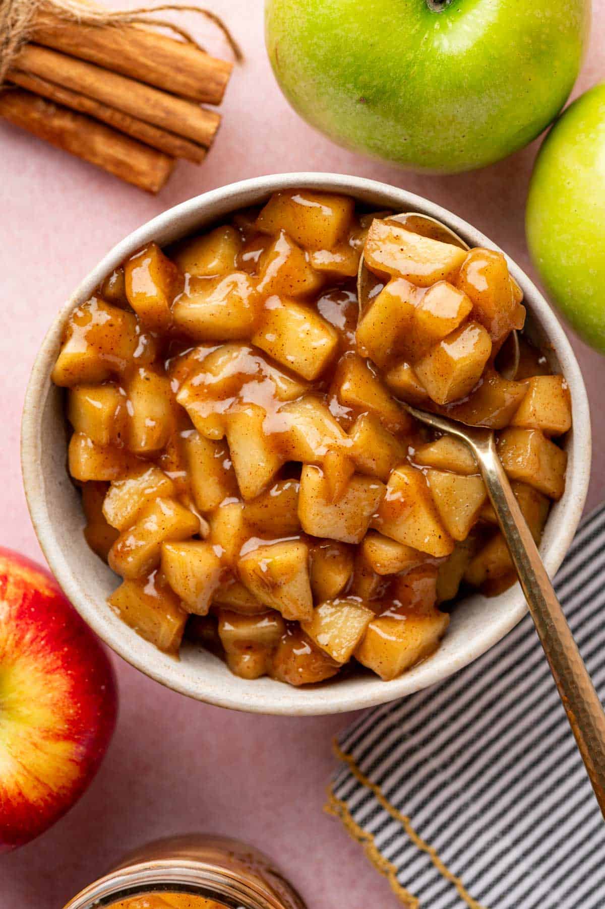 Fresh apple pie filling cooling in a bowl with a spoon on it.