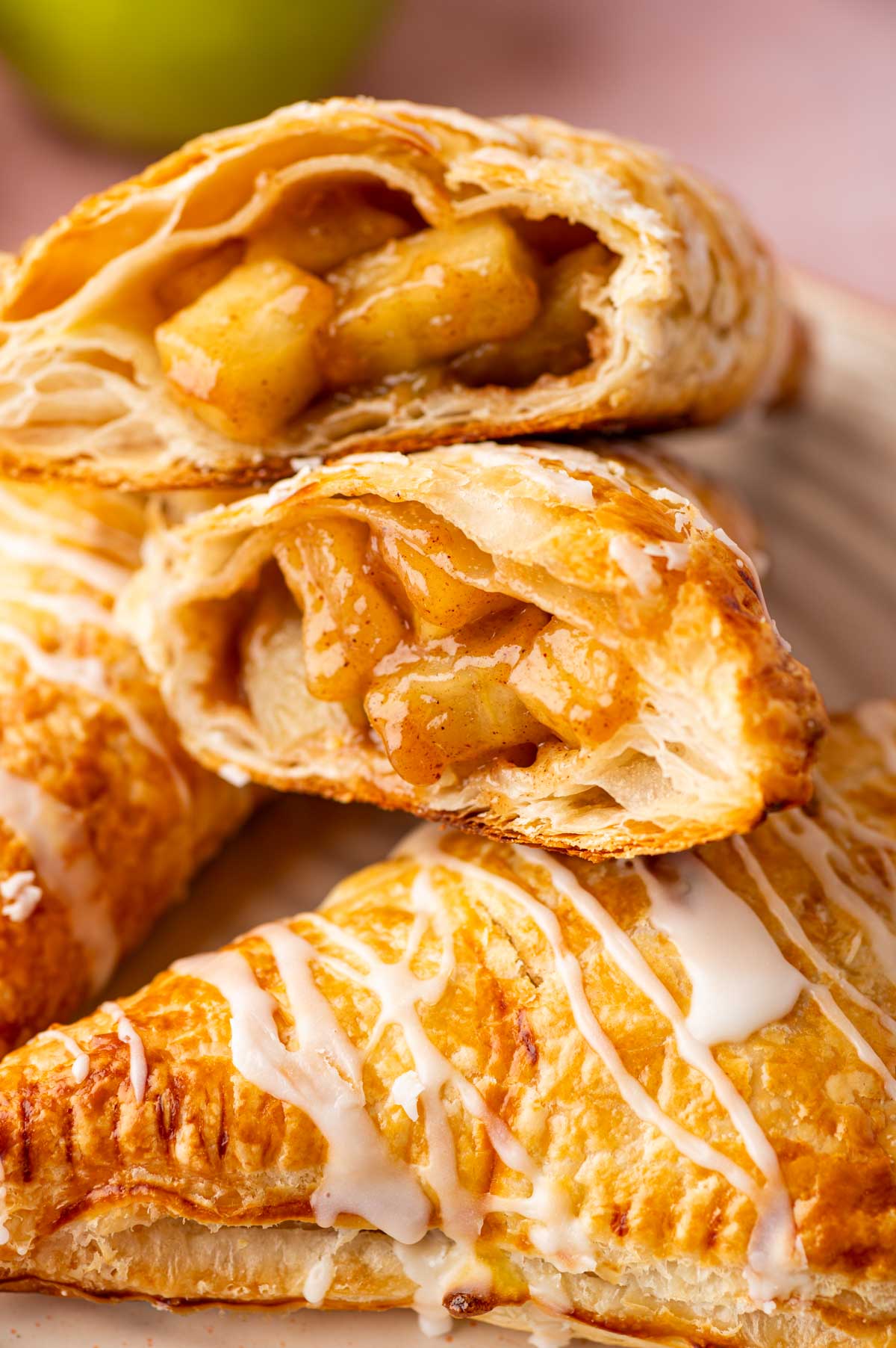 Close-up of warm puff pastry turnovers with glossy apple pie filling inside.