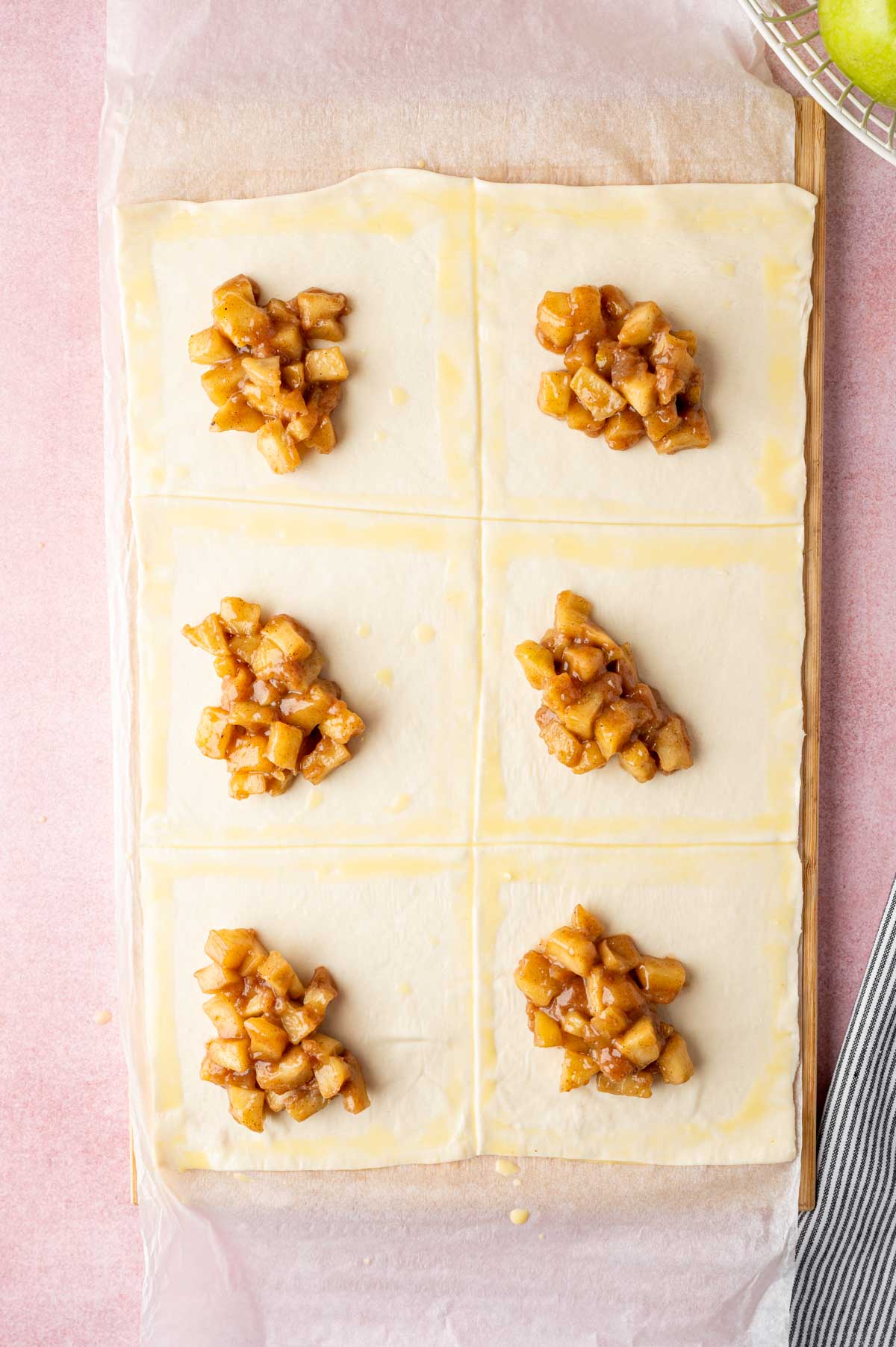 Apple pie filling being placed in the center of the puff pastry.