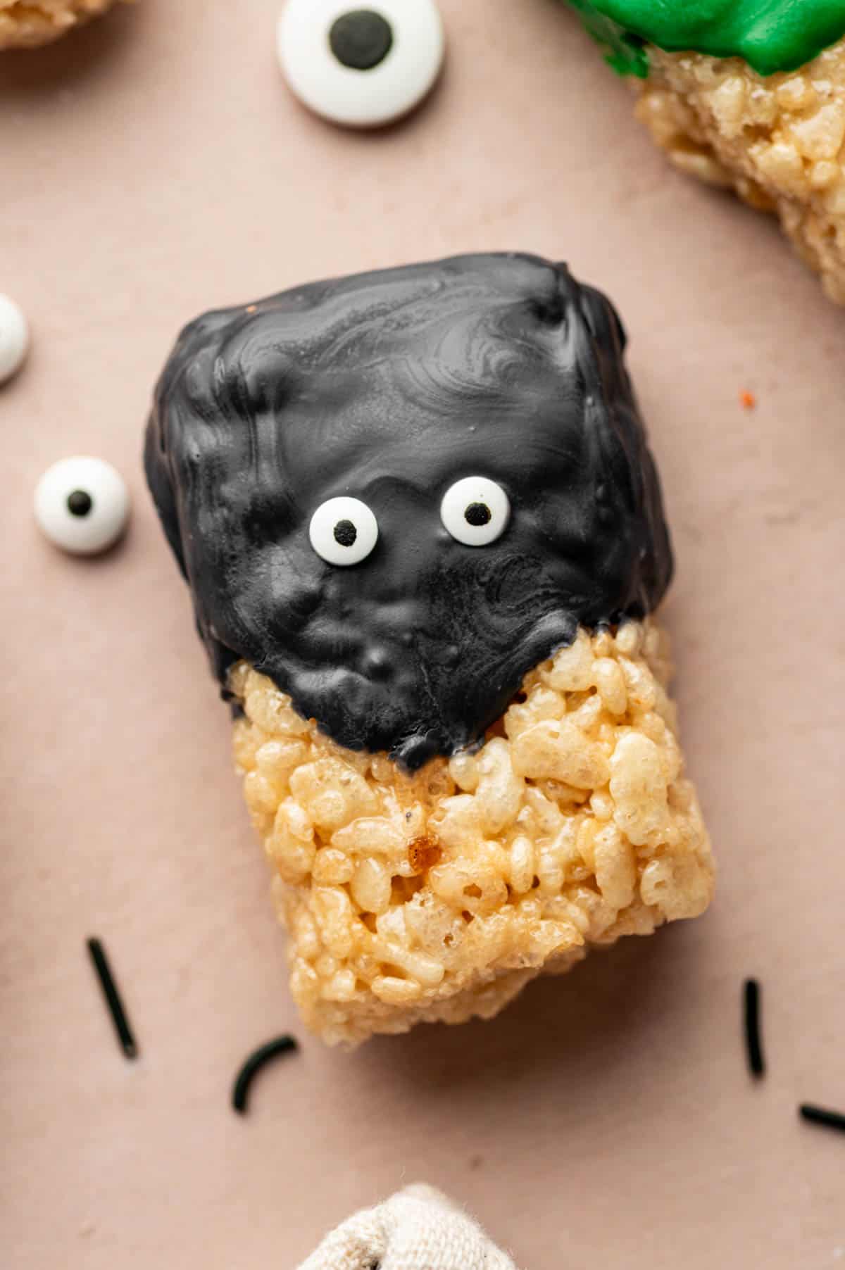 Close-up of Halloween Rice Krispie Treats decorated with candy eyes and black chocolate.