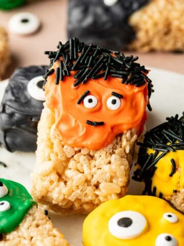 Close-up of Halloween Rice Krispie Treats decorated with candy eyes and drizzled with orange and black chocolate.