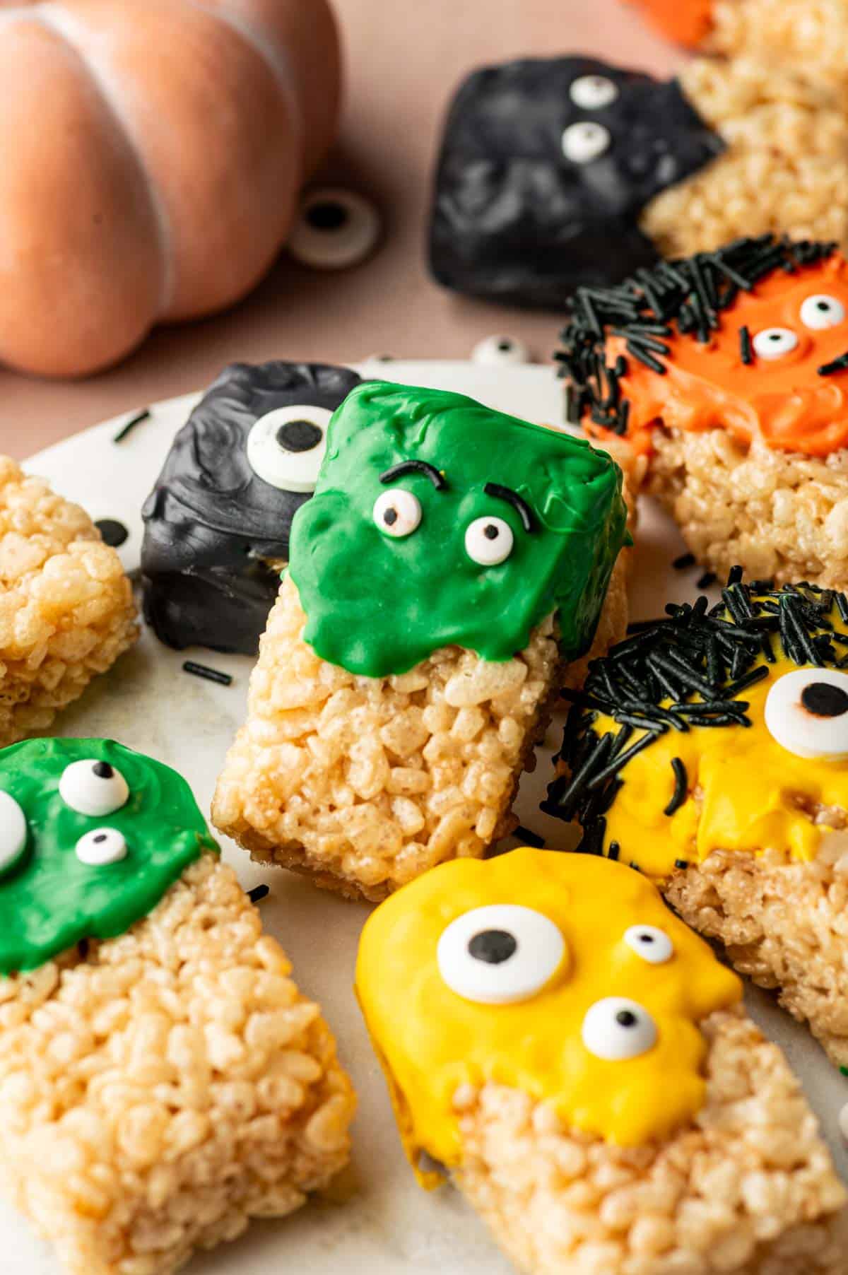 Halloween Rice Krispie Treats stacked on a tray with black, green, and orange sprinkles for a festive party look.
