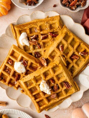 Overhead shot of pumpkin pecan waffles topped with maple syrup and pecans.