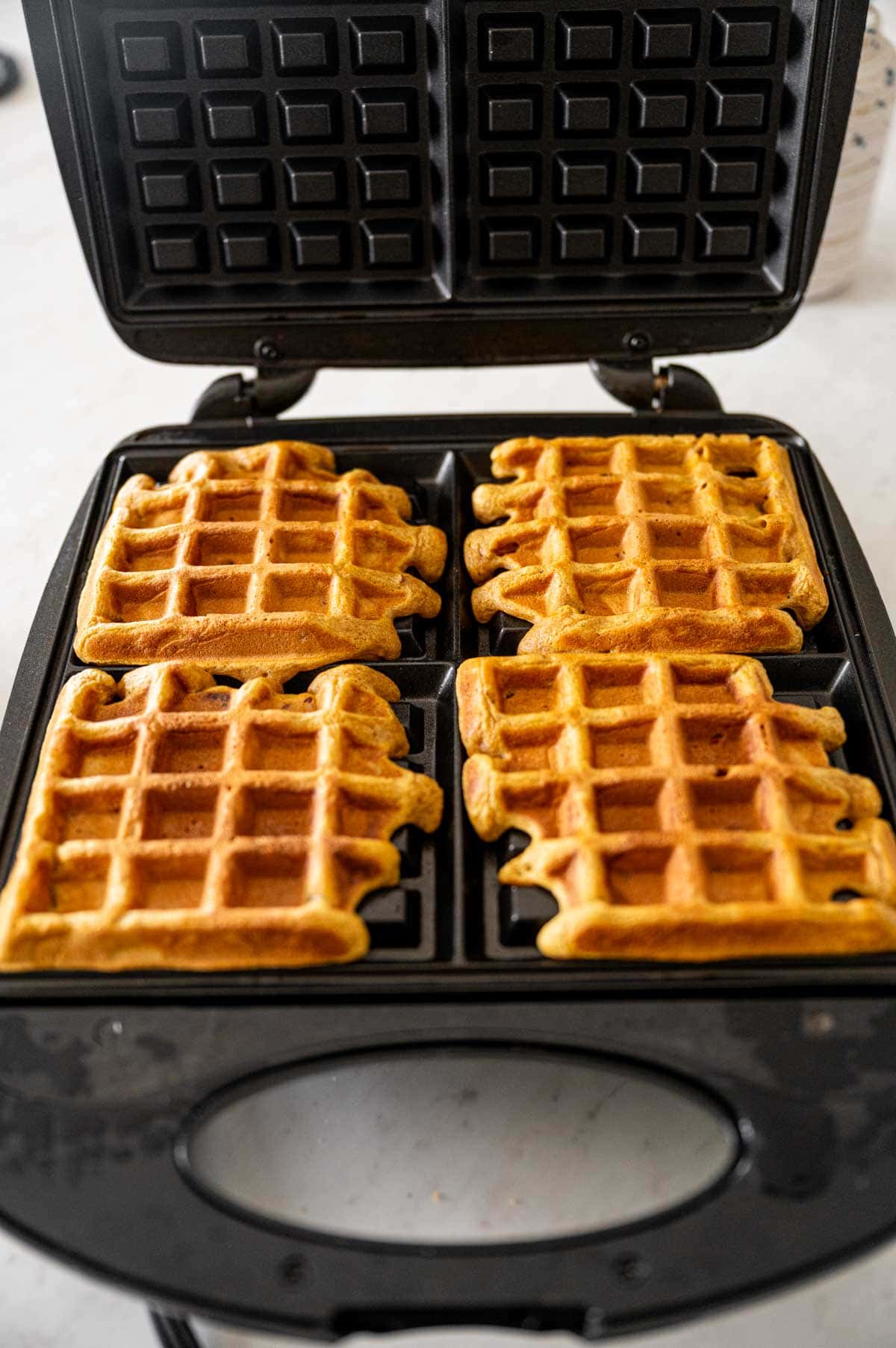 Golden cripy pumpkin pecan waffles in the waffle iron.