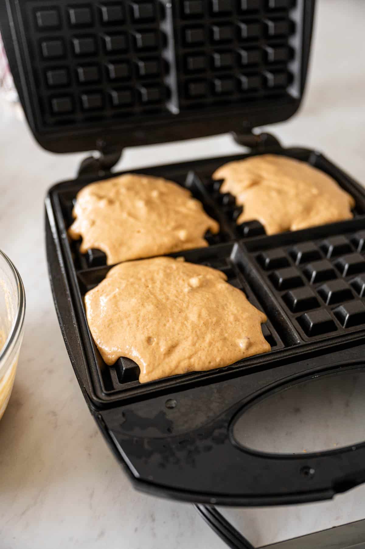 Waffle batter being poured in the waffle maker.
