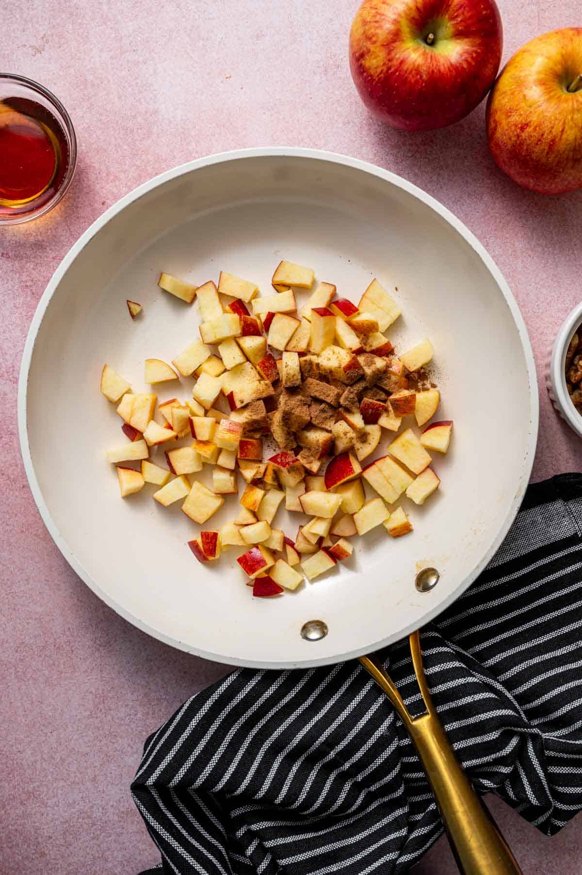 diced apples cooking with cinnamon and maple syrup in a skillet