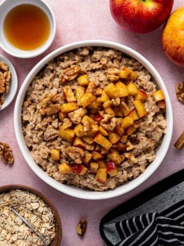 Overhead shot of apple cinnamon oatmeal with maple drizzle, walnuts, apples, etc.,