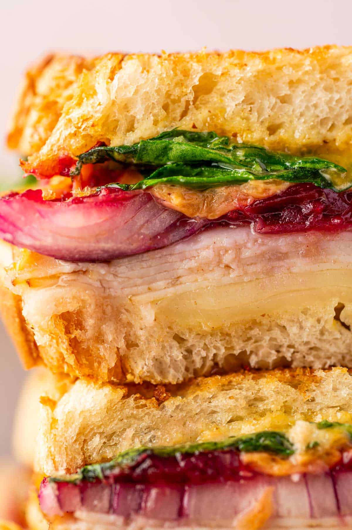 Close-up of turkey melt sandwich with cranberry relish and melted cheese, spinach, onions, air-fried to crispy perfection.