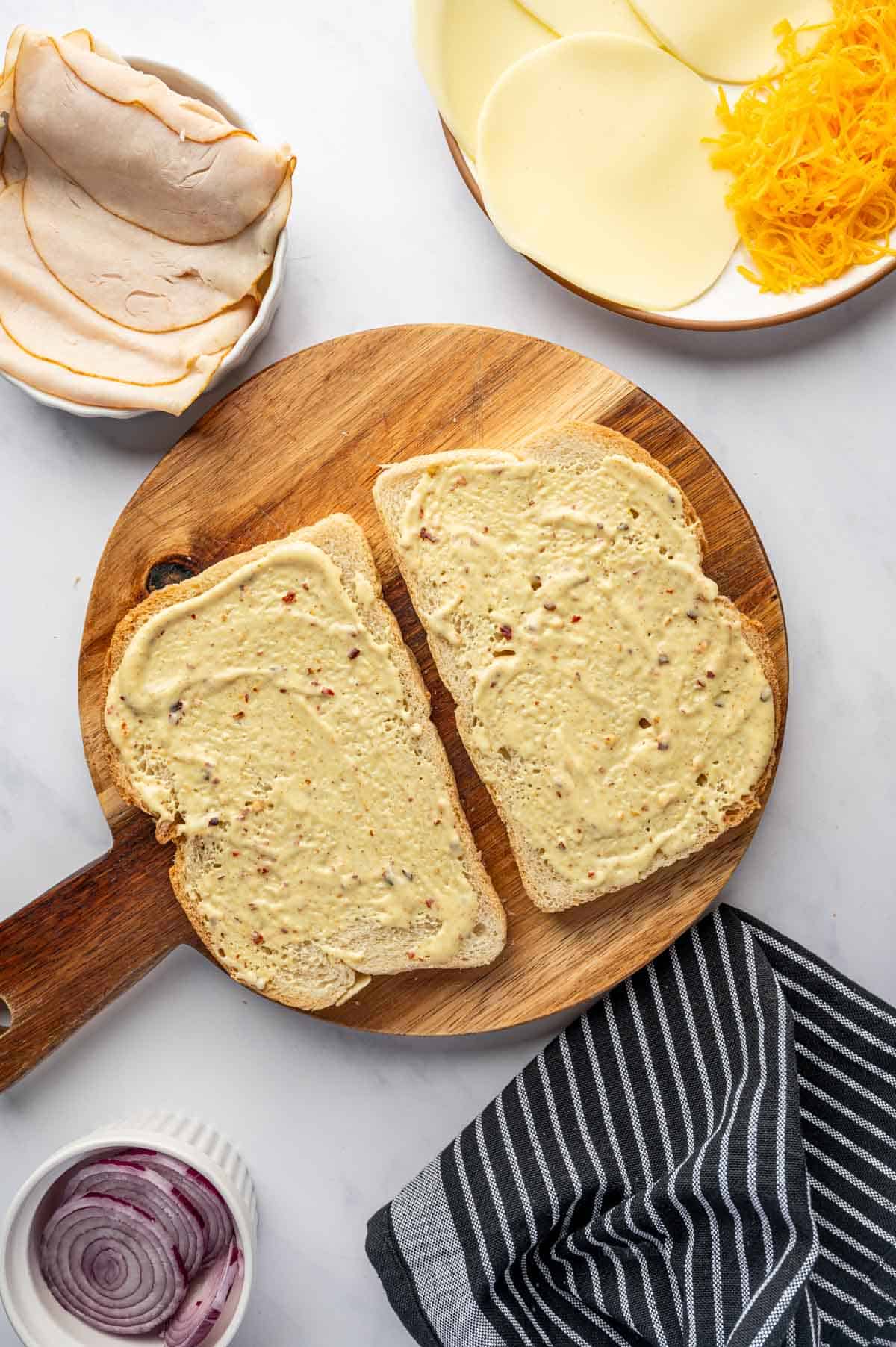 Hot honey Dijon Mayo being spreaded over bread.