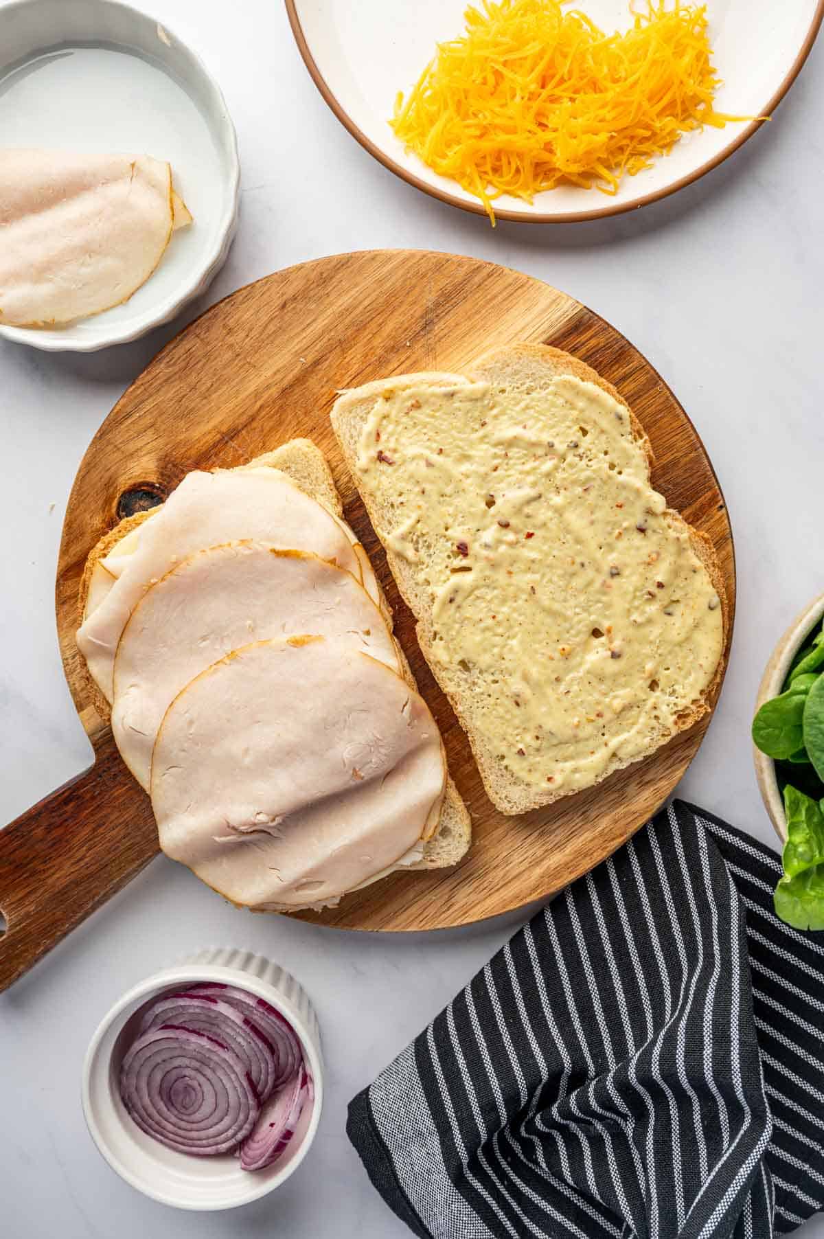 Deli turkey slices being arranged over the sour dough bread.