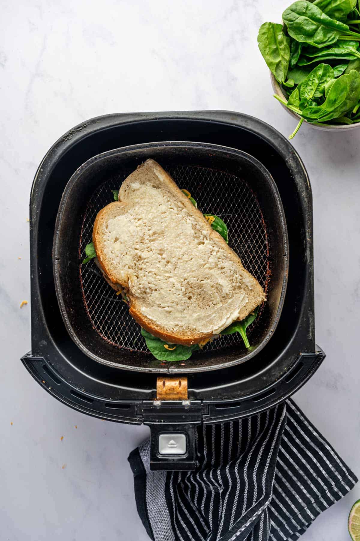 Turkey melt sandwich is ready to air fry in the air fryer basket.
