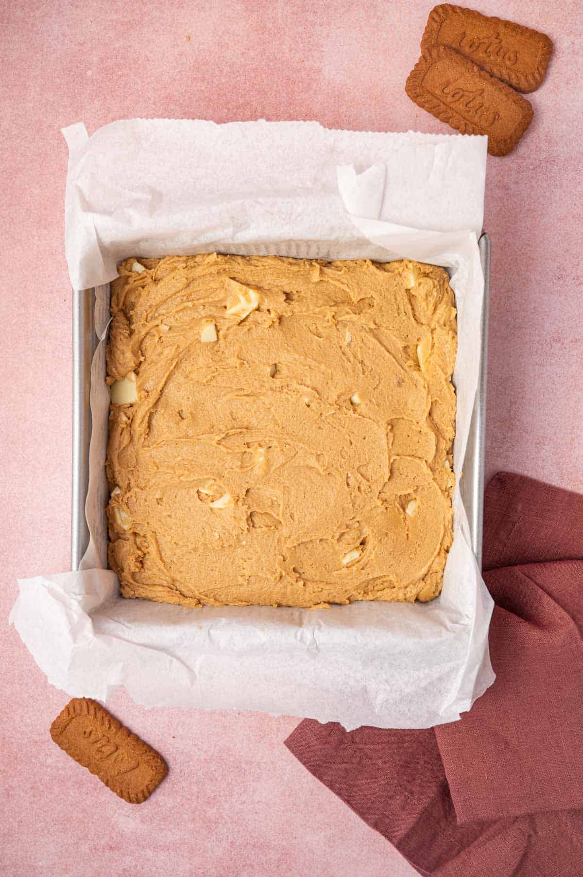 Biscoff blondies batter being transferred to the metal baking pan.