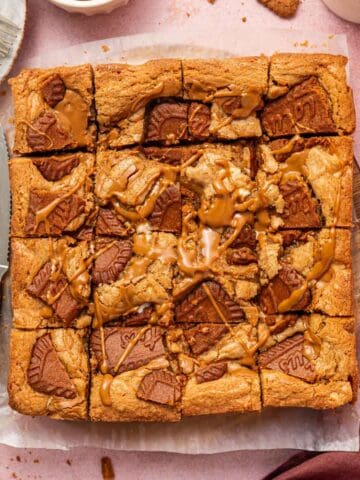 Freshly baked biscoff blondies cooling on parchment paper with nice golden edges.