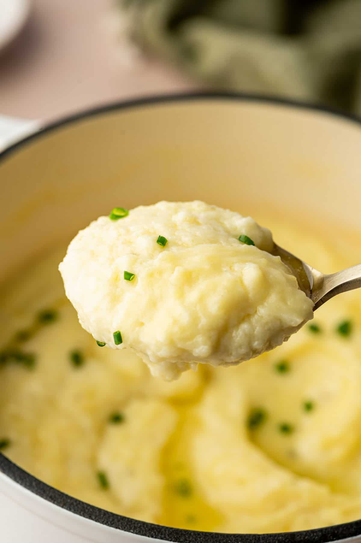 Spoonful of cheesy mashed potatoes showing smooth, creamy texture.