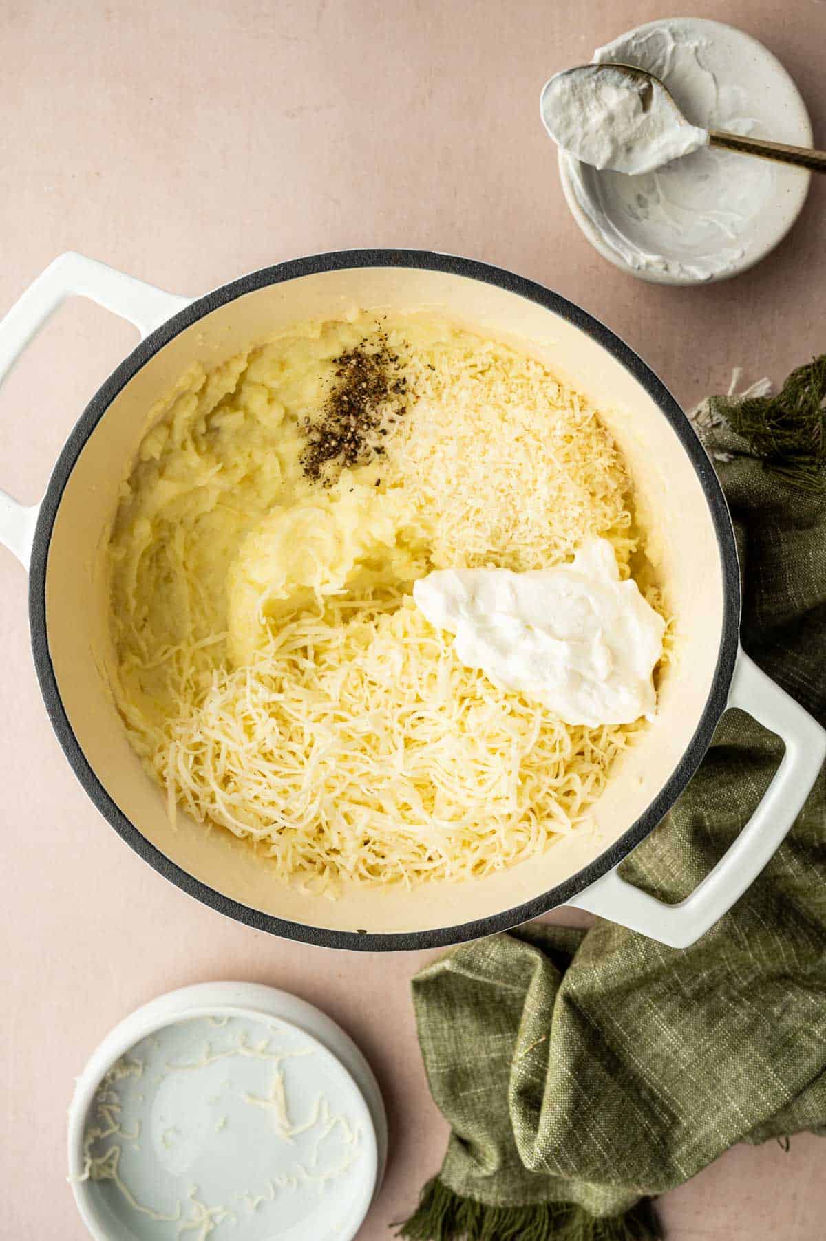 To the mashed potatoes cheeses are being added along with sour cream.