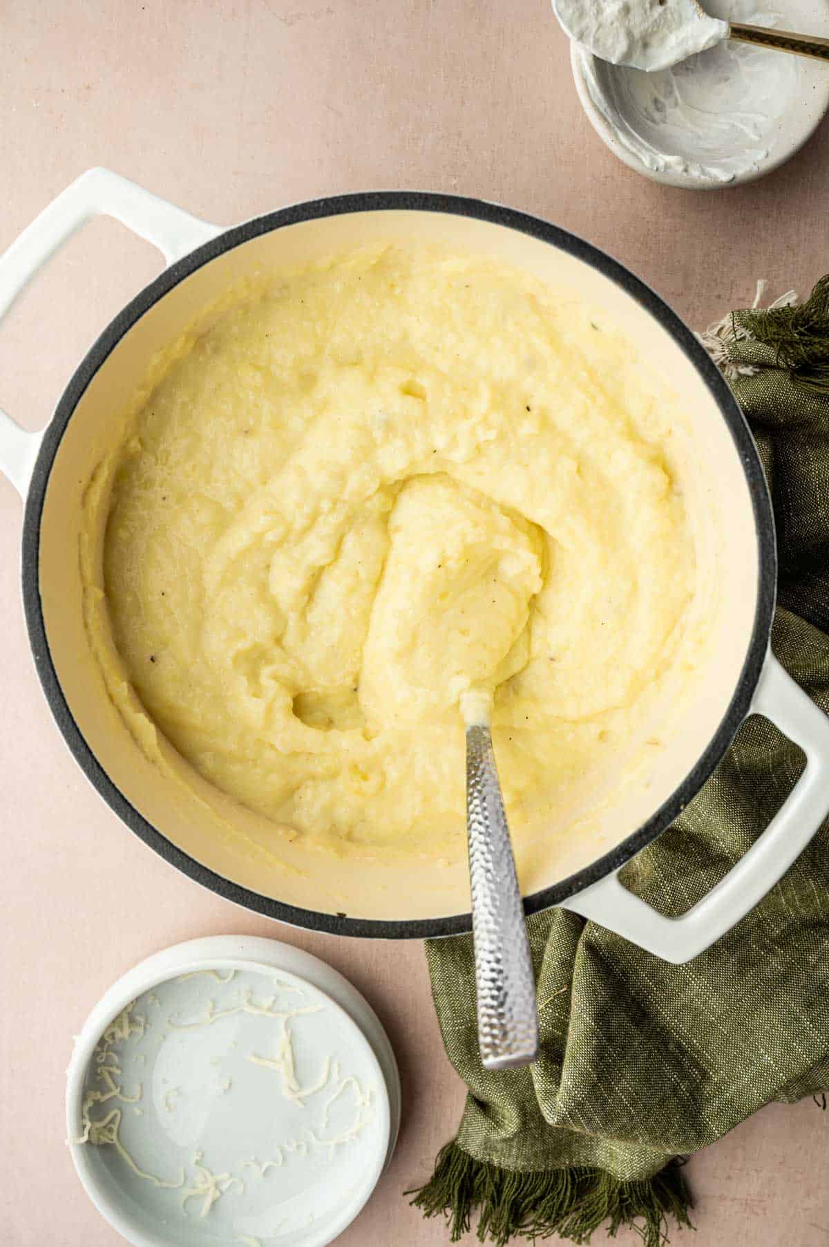 Mashed potatoes being mixed with a spoon on a dutch oven.