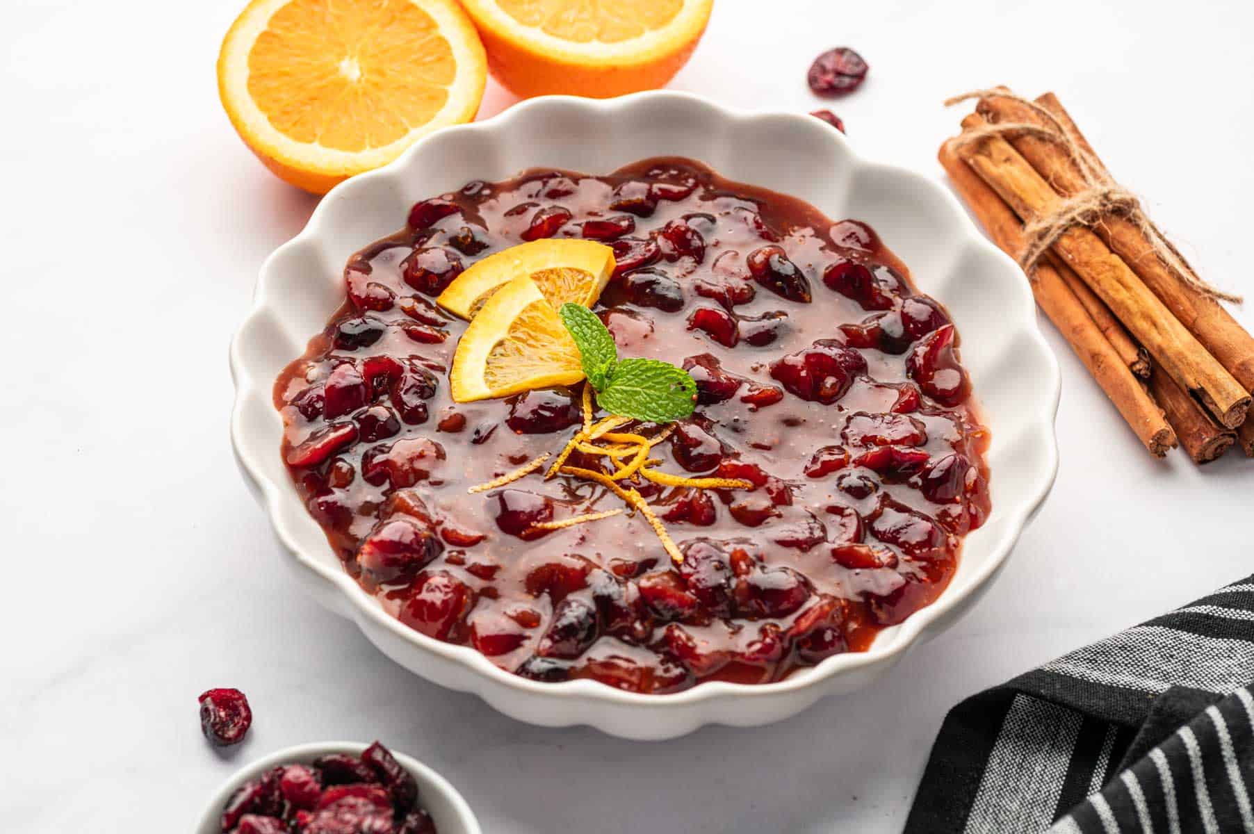 Homemade cranberry sauce made with dried cranberries served in a white bowl on a marble table.