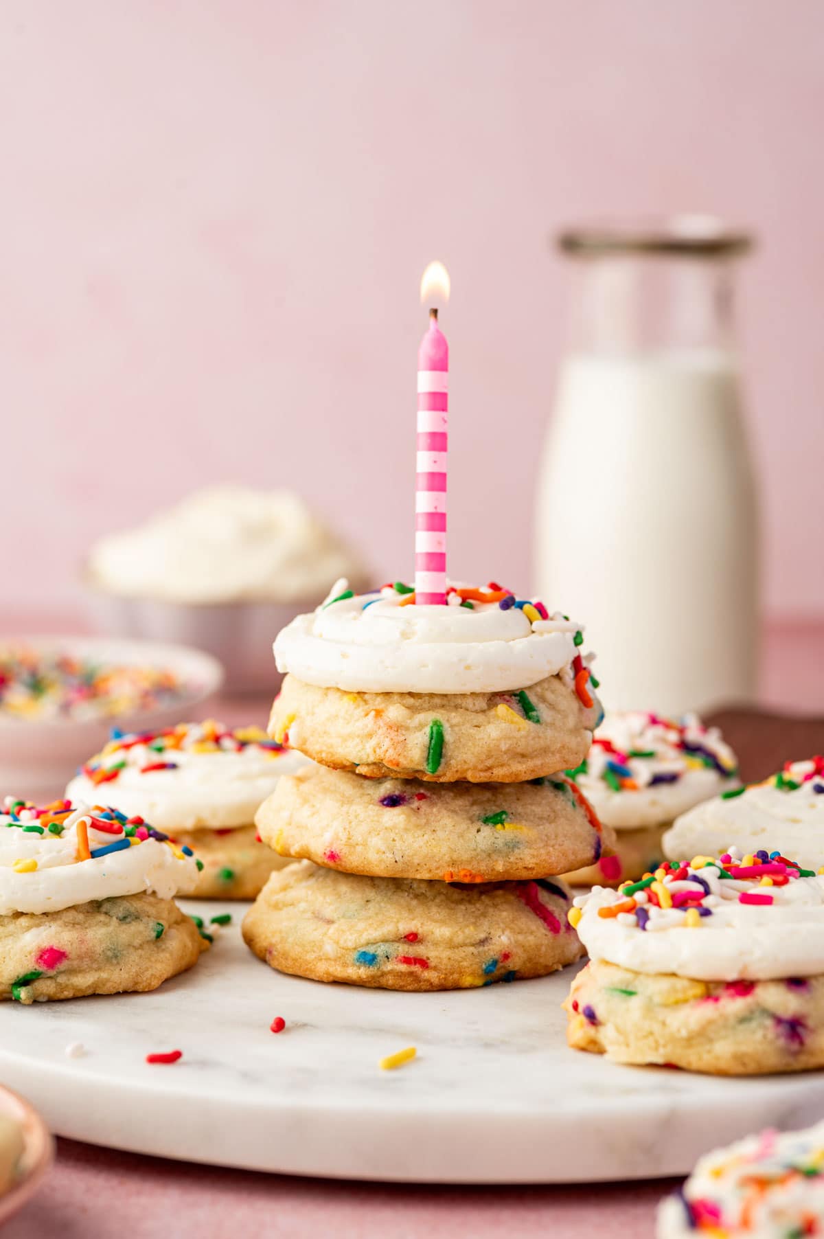 Birthday candle being placed on a stack of funfetti birthday cake cookies.