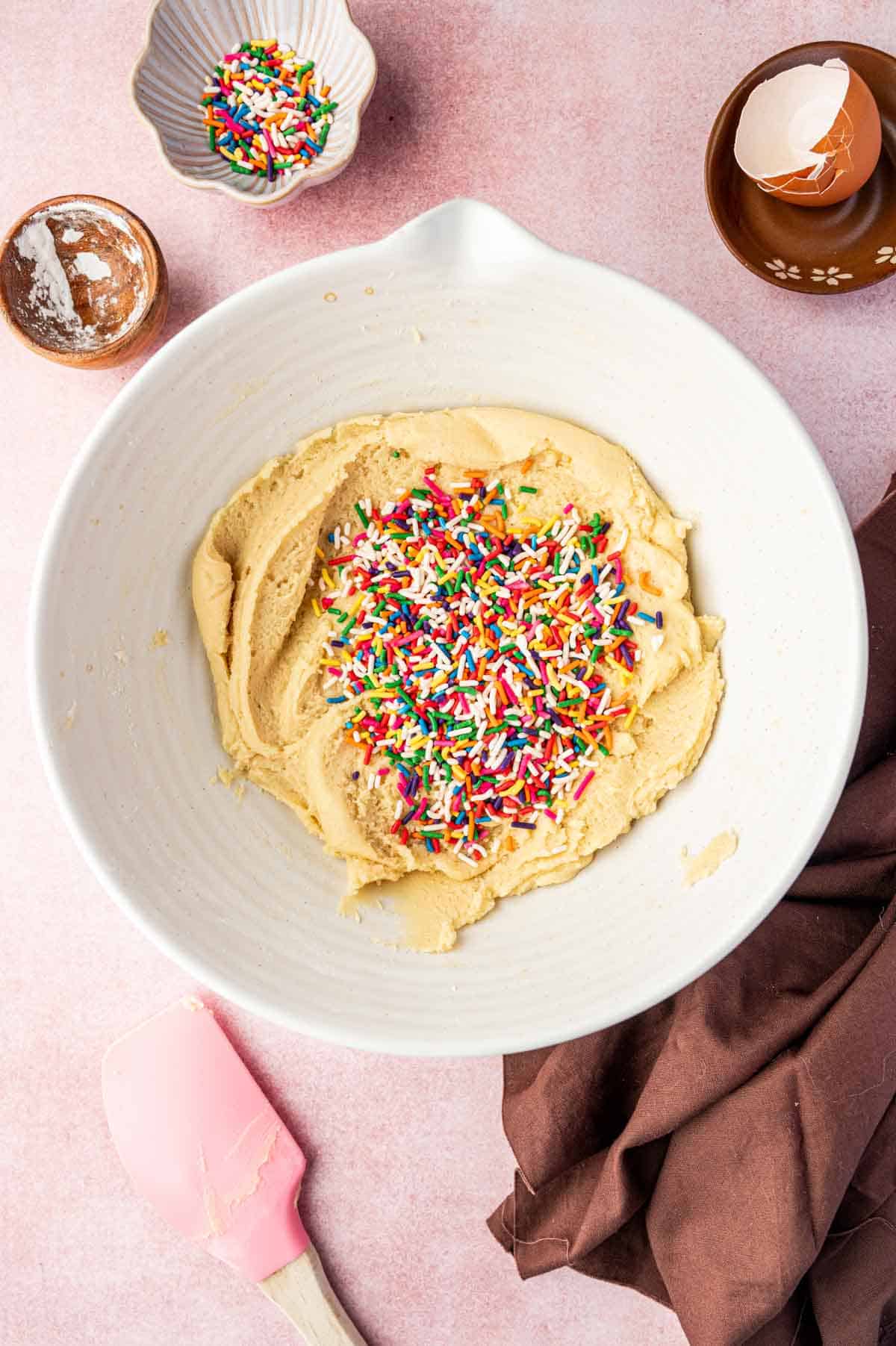 Mixing bowl of funfetti cookie dough with colorful sprinkles folded in.