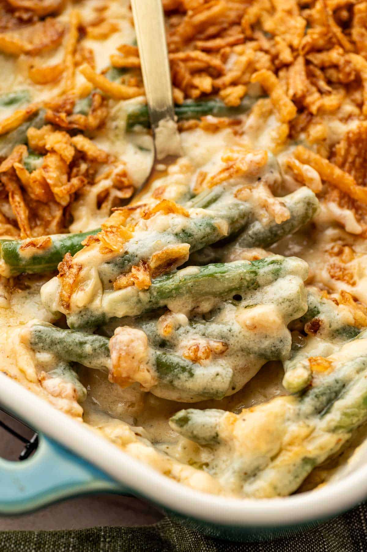 Close-up of green bean casserole with gooey cheese and crunchy topping, made without mushroom soup.