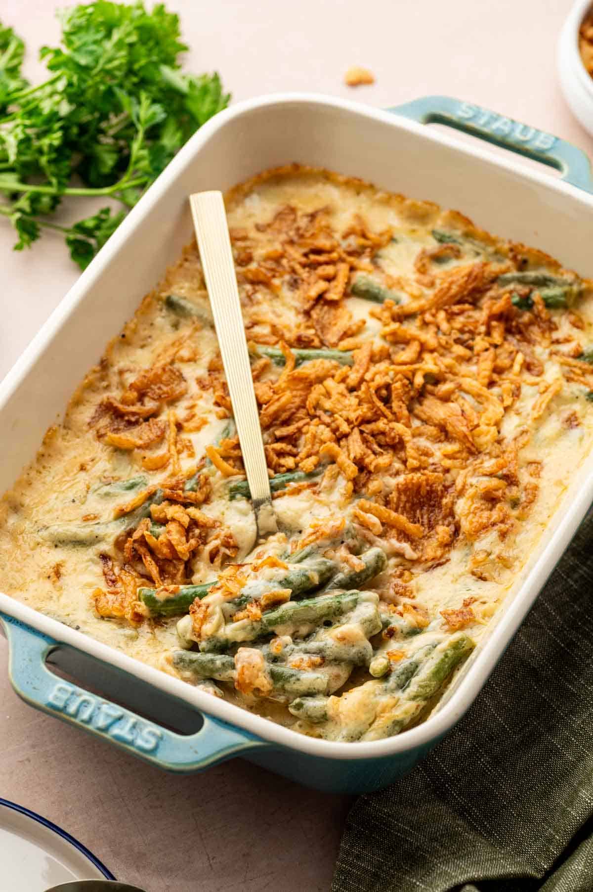 Holiday cheesy green bean casserole with golden brown top, perfect for Thanksgiving dinner, being ready to be scooped.