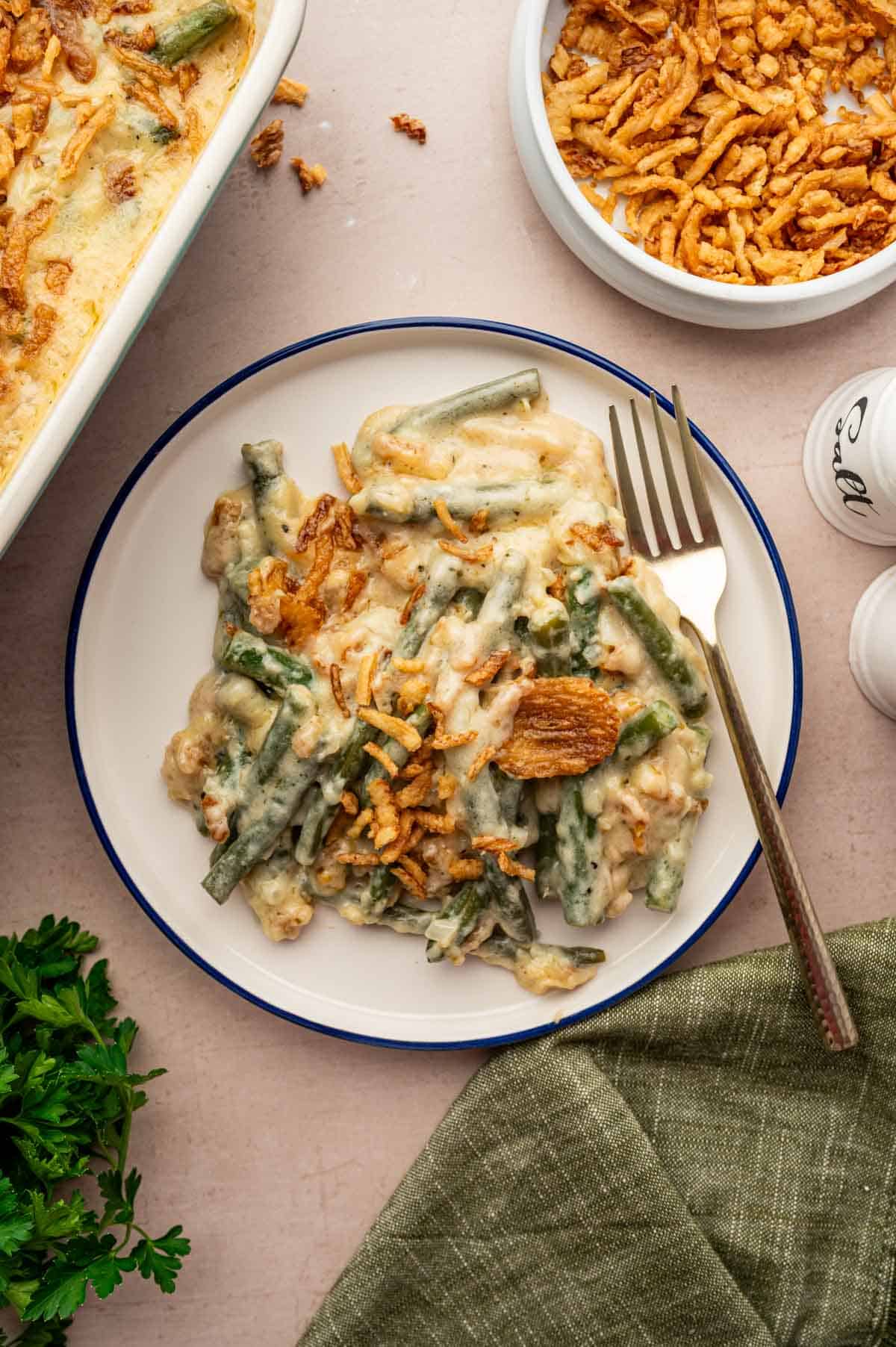 Creamy cheesy green bean casserole from scratch, served hot in a white plate with a crispy, bubbly topping.