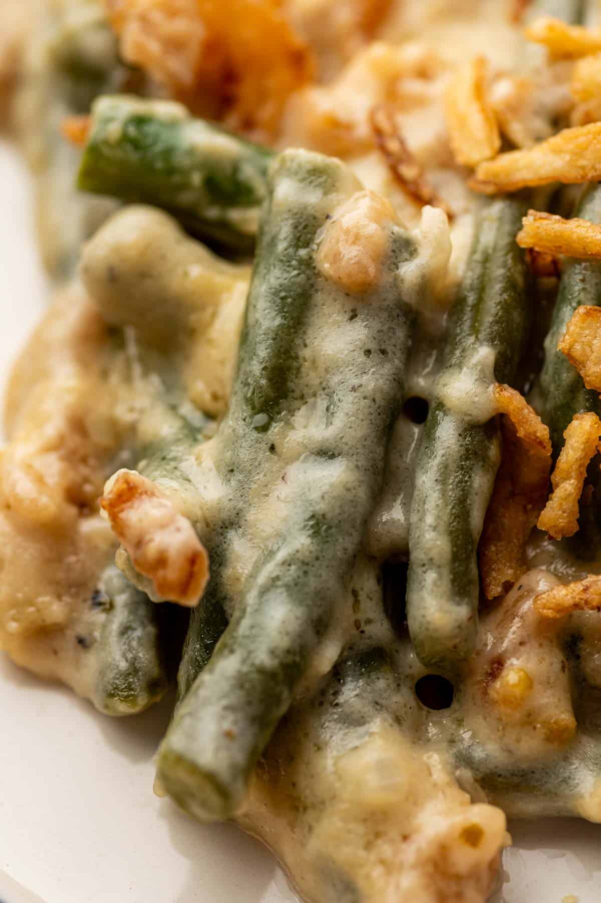 Close-up of green bean casserole with gooey cheese and crunchy topping, made without mushroom soup.