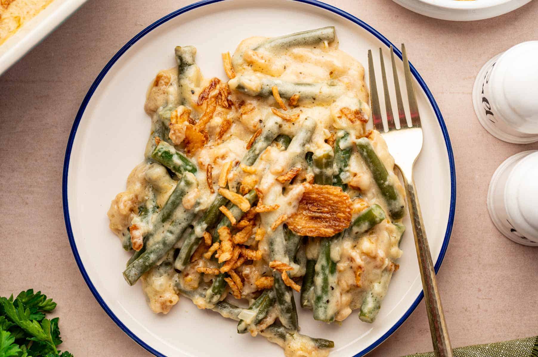 Creamy cheesy green bean casserole served on a serving plate with a golden fork on it.